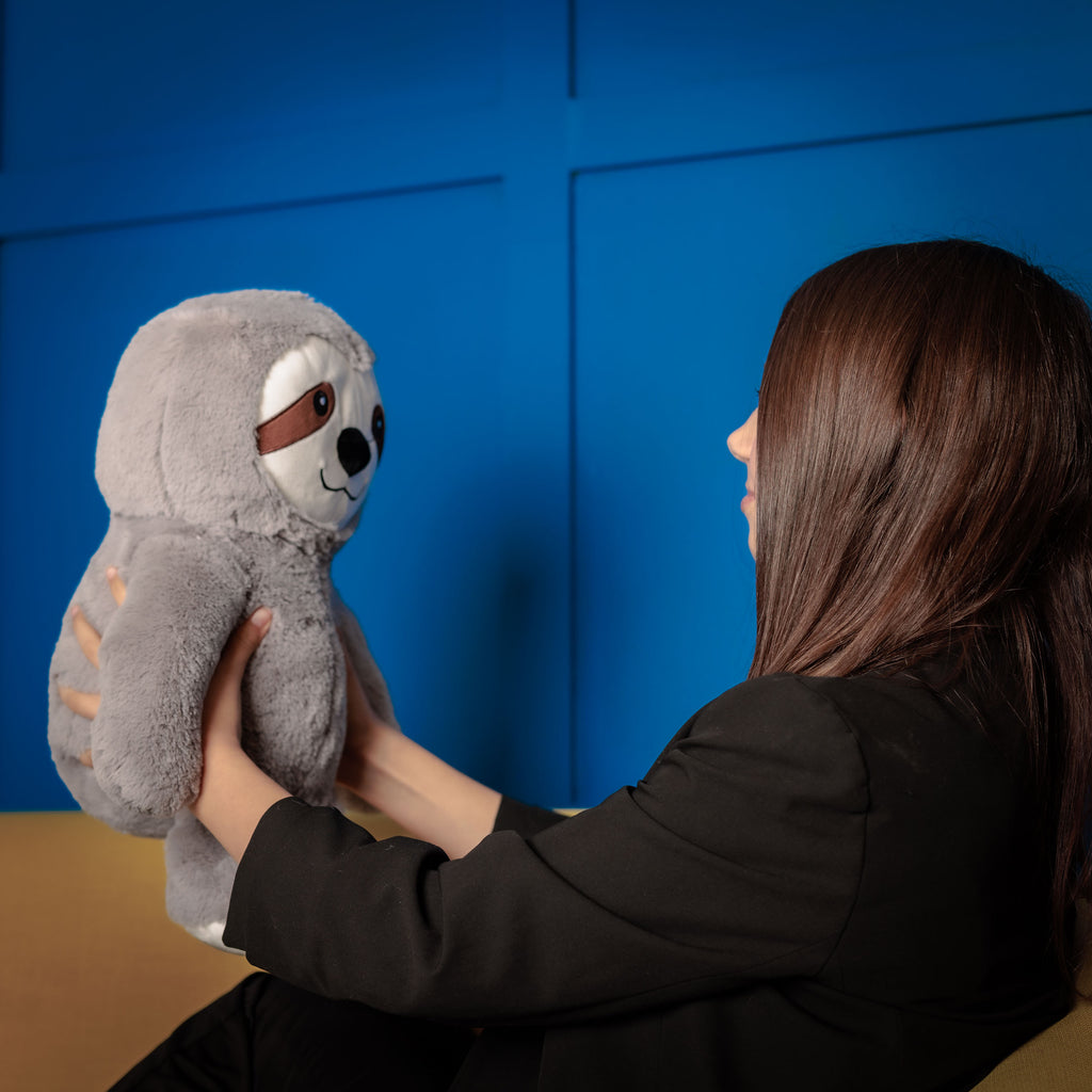 Girl holding a weighted animal in front of her and looking at it happy.